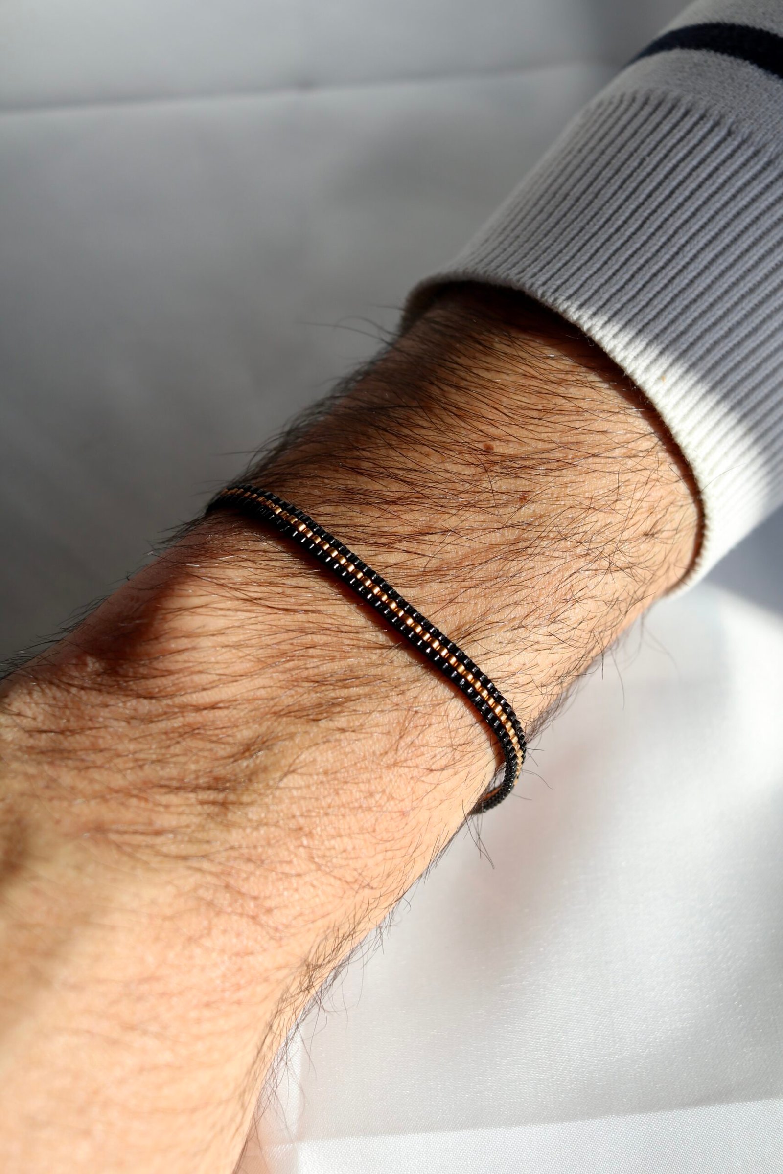 Un bracelet au contraste intense, où le noir profond révèle une ligne centrale couleur bronze, comme une lumière chaude qui bat au cœur de la nuit. Un bijou masculin, élégant et chargé de sens, symbole de force, de loyauté et d’émotions discrètes.