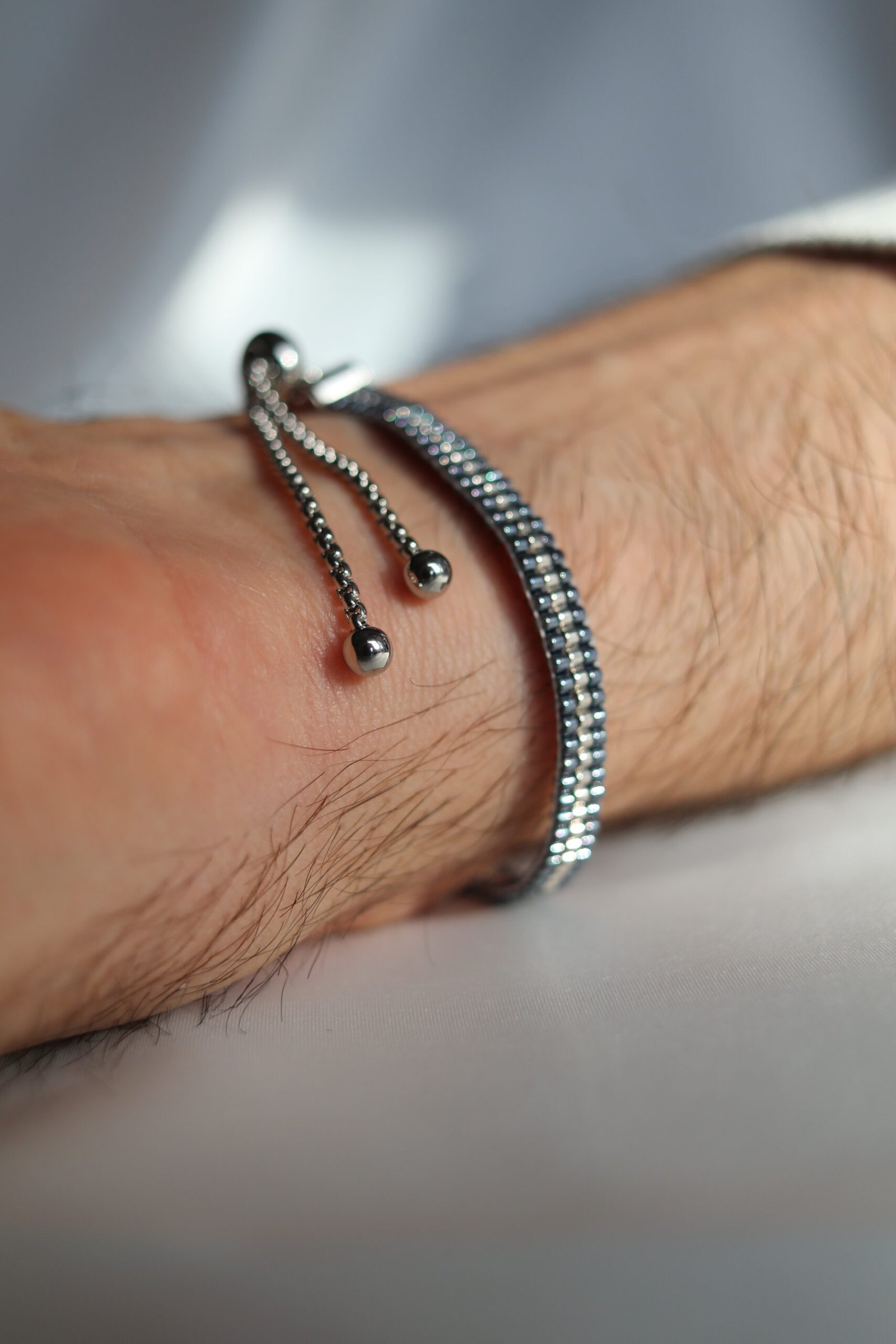 Un bracelet au caractère minéral et lumineux, mêlant un gris argenté palladium à un contour gunmetal bleu acier. Une création sobre, moderne et élégante, pensée comme un bijou intemporel pour homme.