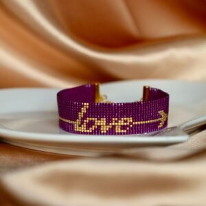 Cupidon est un bracelet large et affirmé, où le mot Love brodé en perles dorées est traversé par une flèche, symbole d’amour éternel et de passion. Un bijou fort, lumineux et profondément romantique.