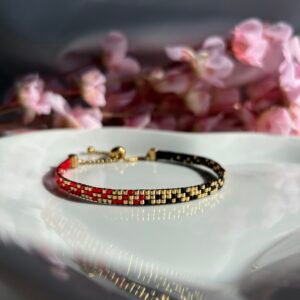 Bracelet fin tissé à la main en perles Miyuki. Une alliance de noir, or et rouge pour symboliser la profondeur, la lumière et l’intensité. Audacieux, intemporel, profondément personnel.