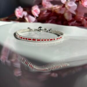 Bracelet tissé à la main en perles Miyuki argents et rouges, le Secret Love – Ruby Silver révèle en code morse le message « I Love U ». Une création lumineuse et passionnée, symbole d’un amour discret mais intense.