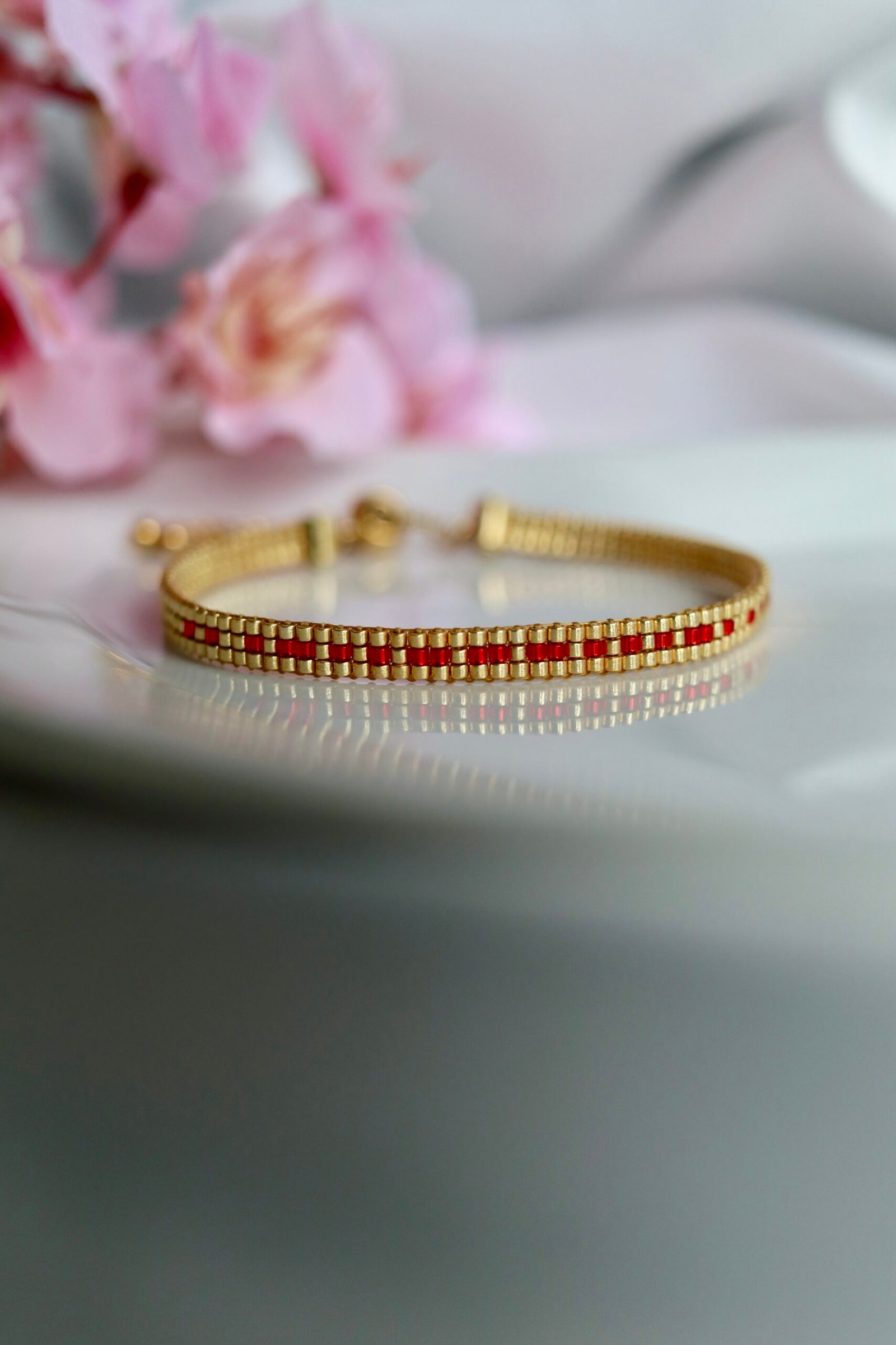Bracelet tissé à la main en perles Miyuki dorées et rouges, le Secret Love – Ruby Gold révèle en code morse le message « I Love U ». Une création lumineuse et passionnée, symbole d’un amour discret mais intense.