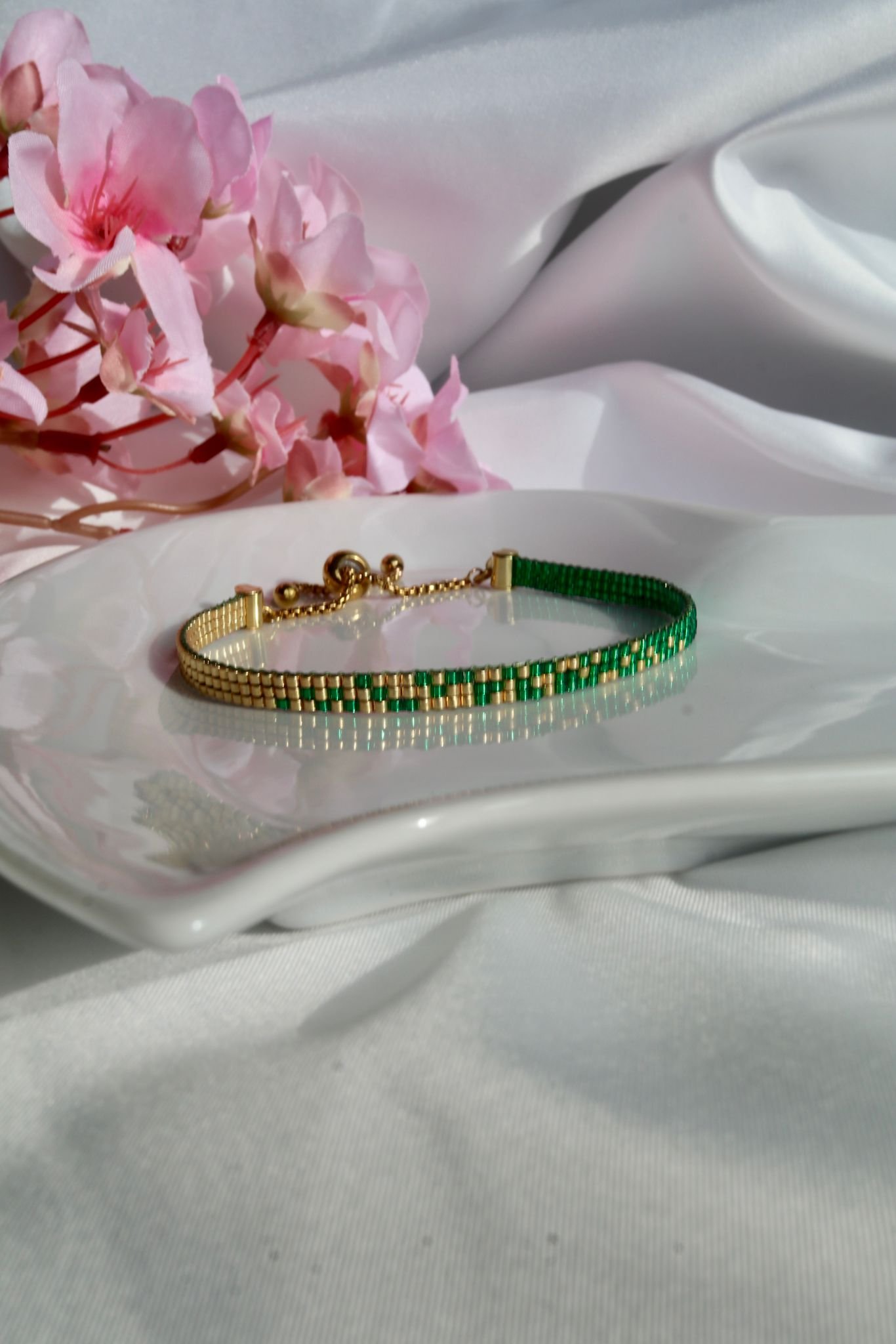 Émeraude d’Or est un bracelet fin tissé à la main en perles Miyuki, mêlant vert profond et or lumineux. Un bijou élégant et intemporel, inspiré par la nature et la lumière.