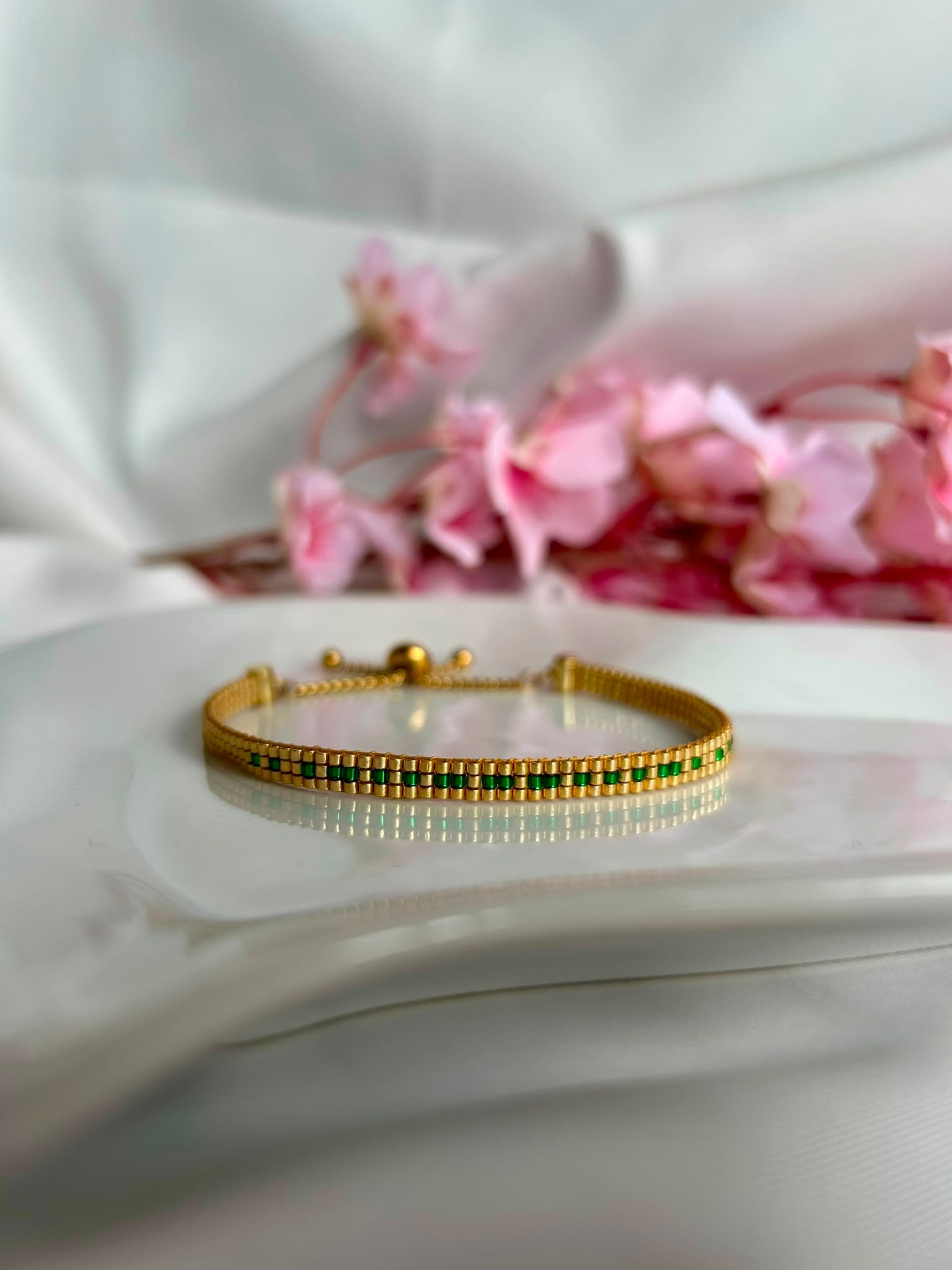 Bracelet tissé à la main en perles Miyuki dorées et vertes, le Secret Love – Emerald Gold révèle en code morse le message « I Love U ». Une création lumineuse et passionnée, symbole d’un amour discret mais intense.