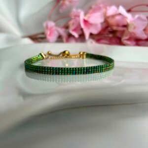 Bracelet fin tissé à la main en perles Miyuki. Inspiré des ailes délicates d'une libellule, Ailes d'Émeraude révèle de magnifiques reflets verts, turquoise et violets qui évoluent au gré de la lumière. Élégant, mystérieux et lumineux, il apporte une touche de nature et de magie à votre poignet.