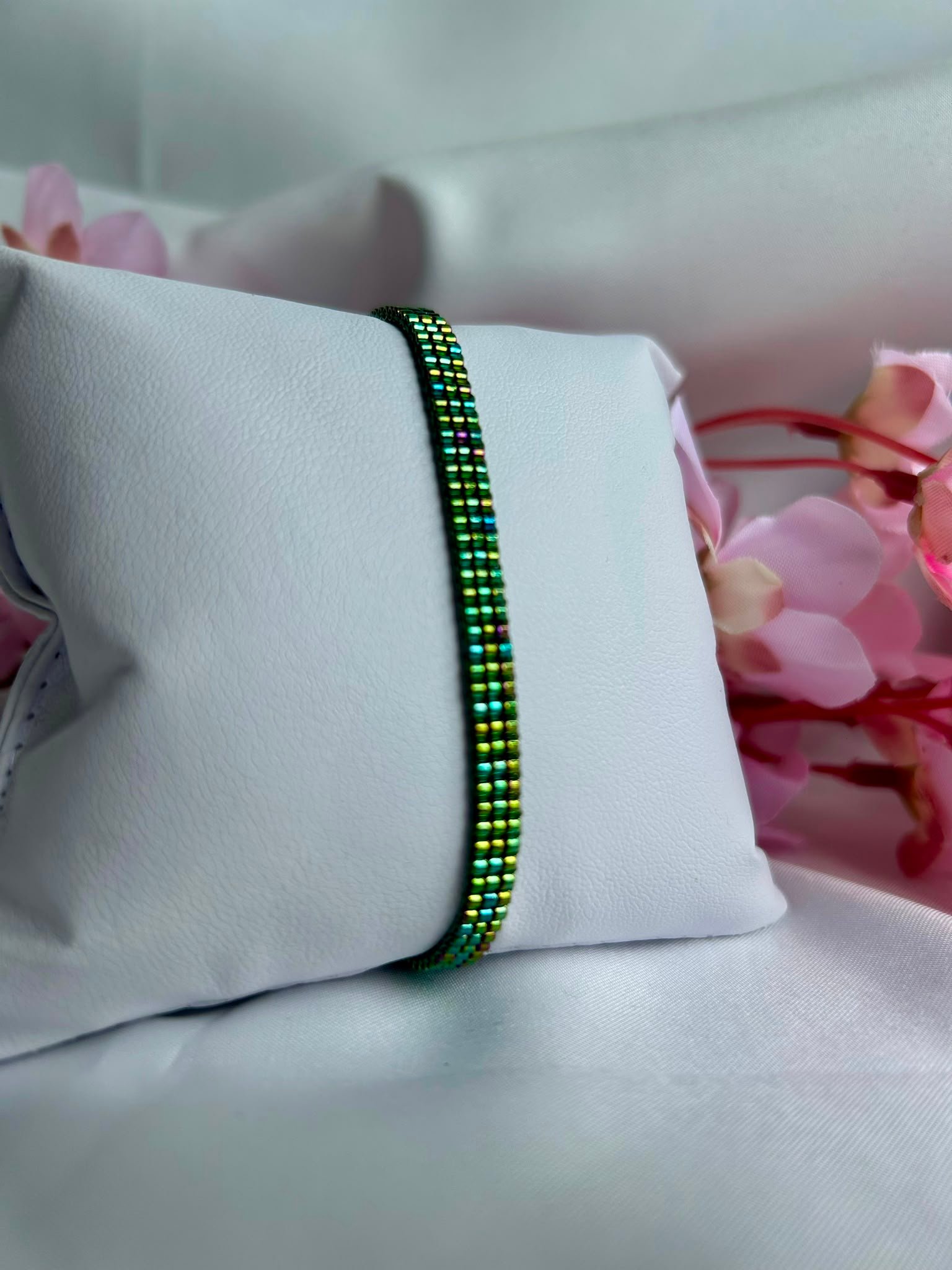 Bracelet fin tissé à la main en perles Miyuki. Inspiré des ailes délicates d'une libellule, Ailes d'Émeraude révèle de magnifiques reflets verts, turquoise et violets qui évoluent au gré de la lumière. Élégant, mystérieux et lumineux, il apporte une touche de nature et de magie à votre poignet.